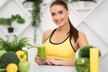 Sports nutrition. Excited girl holding glass with green detox drink
