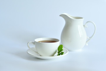 Obraz na płótnie Canvas One small cup of tea with mint and jug on white background.