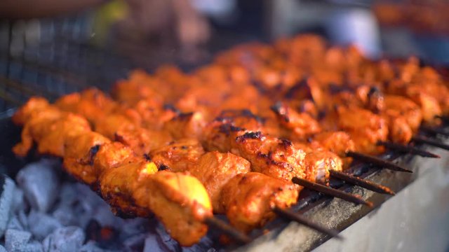 Paneer fish chicken tikka roasting on an open hearth with glowing coals and smoke coming out