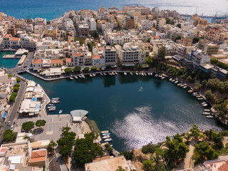 Naklejka premium Lake Voulismeni in Agios Nikolaos on Crete island in Greece, in frame the boats and city streets, houses of local residents, aerial photography