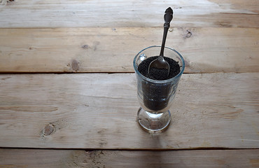 Amaranth seeds in a glass with a small spoon.