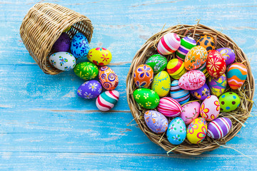 Easter holiday concept,Colorful Easter eggs in basket on blue pastel color rustic wood background with space.
