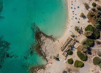 Top down view of the beach by the Mediterranean Sea, azure clear water and tourists on the beach resting under beach umbrellas, Aerial photography