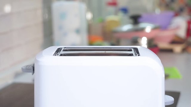 white toast bread in two-slot automatic electric toaster. making toast for Breakfast