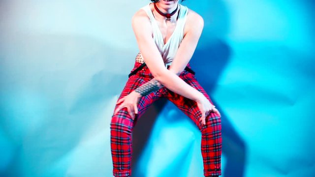 A woman in high heels makes dance moves at a kinky party. Hands lie on his knees, makes cross-motion. The concept of a person&rsquo;s good mood.
