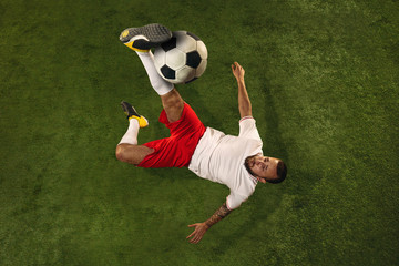 Top view of caucasian football or soccer player on green background of grass. Young male sportive...