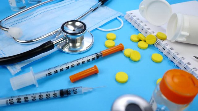 Syringe for Insection, Yellow tablets and Stethoscope As Background. Vaccine and paper notebook. Concept of clinic or hospital, health care or doctor. Medical Equipment on blue surface