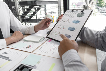 Two business people  are discussing about business graph on the table in the office room