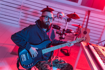 Fototapeta na wymiar Create music and a recording studio concept - Bearded funny man guitarist recording electric guitar track in home studio