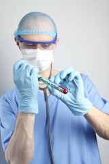 male doctor in a blue uniform with a stethoscope in a protective mask and glasses performs...
