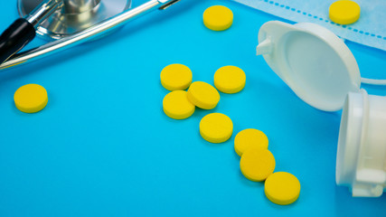 Phonendoscope and plastic bottle with yellow tablets. Pharmaceutical medicament. Novel coronavirus, denoted 2019-nCoV concept.