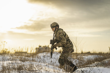 equipped army soldier Man in the winter khaki camouflage is patrolling or patrol field territory. commandos with full equipment helmet and gun watch battlefield. Modern army soldier