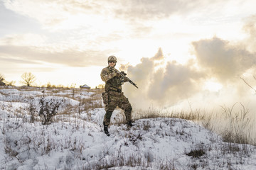 equipped army soldier Man in the winter khaki camouflage is patrolling or patrol field territory. commandos with full equipment helmet and gun watch battlefield. Modern army soldier