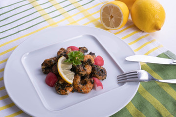 on table lemon and shrimp dish on a white plate