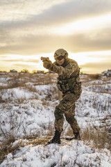Fototapeta premium equipped army soldier Man in the winter khaki camouflage is patrolling or patrol field territory. commandos with full equipment helmet and gun watch battlefield. Modern army soldier