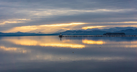  Lake Champlain in Vermont with view of vibrant sunset and the New York Adirondack mountains in winter 