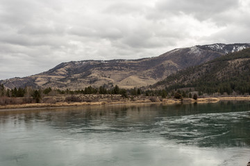 Calm green river in front of tree covered rolling hills