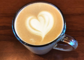 Cup of Cappuccino coffee on wooden table, hot drink close up