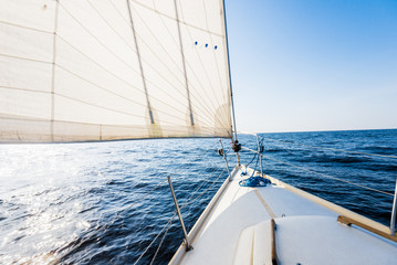 White yacht sails on a clear sunny day. A view from the deck to the bow and sails, close-up. Baltic sea, Latvia