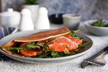 Crepe with arugula and salmon for breakfast on the kitchen table. Good morning.