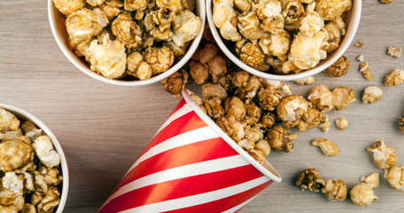 many cups and one red cardboard cup with sprinkled sugar popcorn on a wooden table