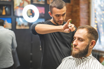 Haircut at the hairdresser. Barber cuts the hair on the client's head. The process of creating...