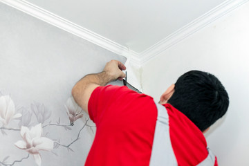 Painter glues Wallpaper. Repairs in the house. Professional master painter.