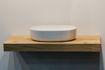 Modern bathroom washbasin. White washbasin in the form of a bowl on a wooden table