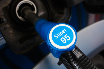 Close up of isolated petrol nozzle in opening of car tank filling with super 95 octane