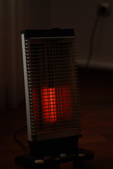 Vintage electric heater Ugolek with a burning lamp in dark living room