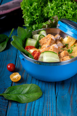 Roasted turkey fillet and potato with fresh vegetable salad in a blue lunch box