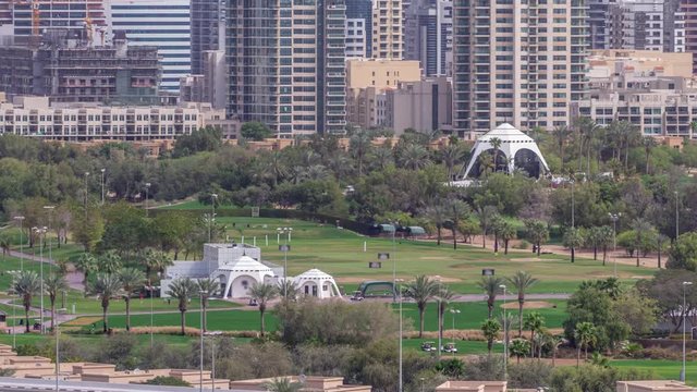 Dubai Golf Course with a cityscape of Gereens and tecom districts at the background aerial timelapse. Traffic on sheikh zayed road with junction