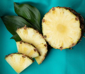 Sliced Pineapple on a turquoise background. Juicy fruit - summer mood with bright colors. On a wooden board and on a bright blue background. Yummy.