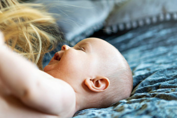 Cute six month baby boy giggling and playing with mothers hair. Closeup, copy space, selective...