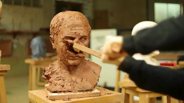 Clay bust face being destroyed by a huge stick