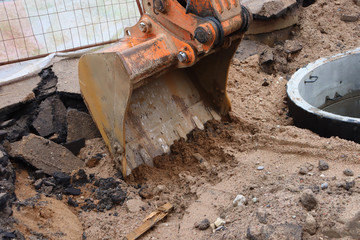Excavator bucket in the ground. Excavator bucket removes a layer of earth and asphalt