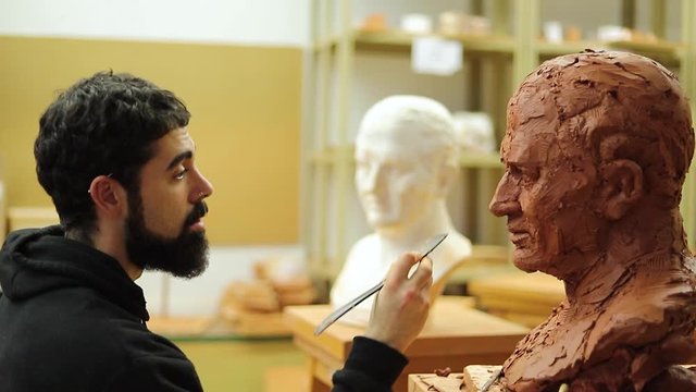 Clay sculptor making a clay bust in an art studio