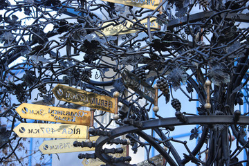 Black wrought iron grape bush with golden road signs.