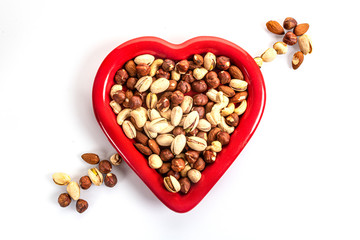 red heart-shaped plate full of nuts on a white background