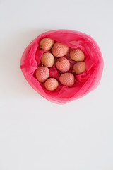 Fresh lychee in pink eco bag isolated on the white background.