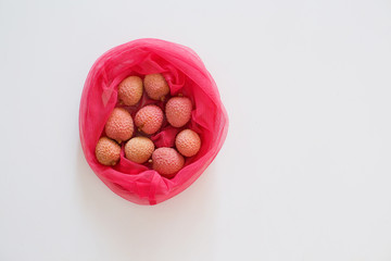 Fresh lychee in pink eco bag isolated on the white background.