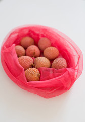 Fresh lychee in pink eco bag isolated on the white background.