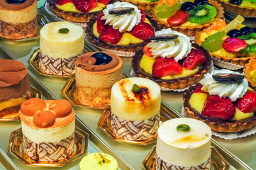 Pastries, fancy cakes and cupcakes on display in pastry shop / bakery