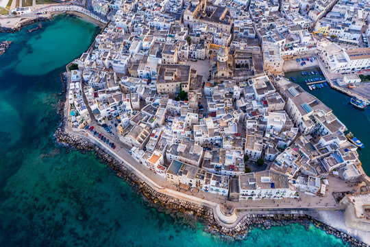 Italy, Apulia, Monopoli, Aerial view of sea and old town at sunset