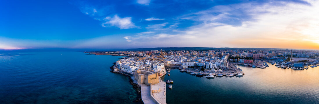 Italy, Apulia, Monopoli, Aerial view of sea and old town at sunset