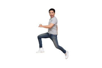 Excited Asian young man in gray t-shirt jumping while celebrating success isolated over white...