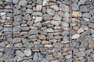 Close-up of gabion, fence made of stones in metal mesh for use in civil engineering, road building landscaping.