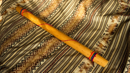Top view of Rain stick on a colorful Peruvian textile. Traditional music concept.