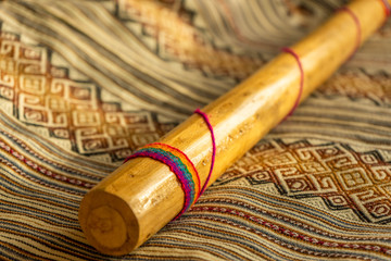 Close up view of a rain stick on a Peruvian textile. Andean music concept.