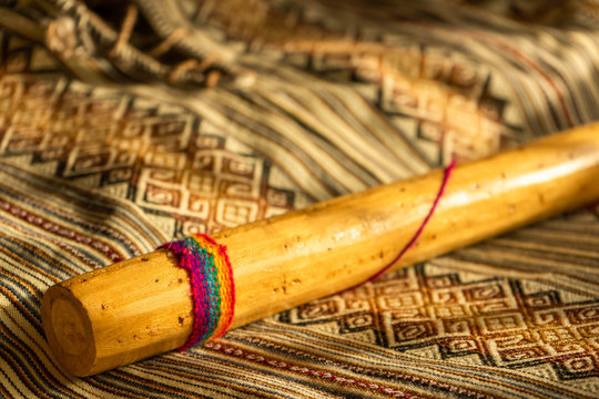 Close up view of a rain stick on a colorful Peruvian poncho. Andean music concept.
